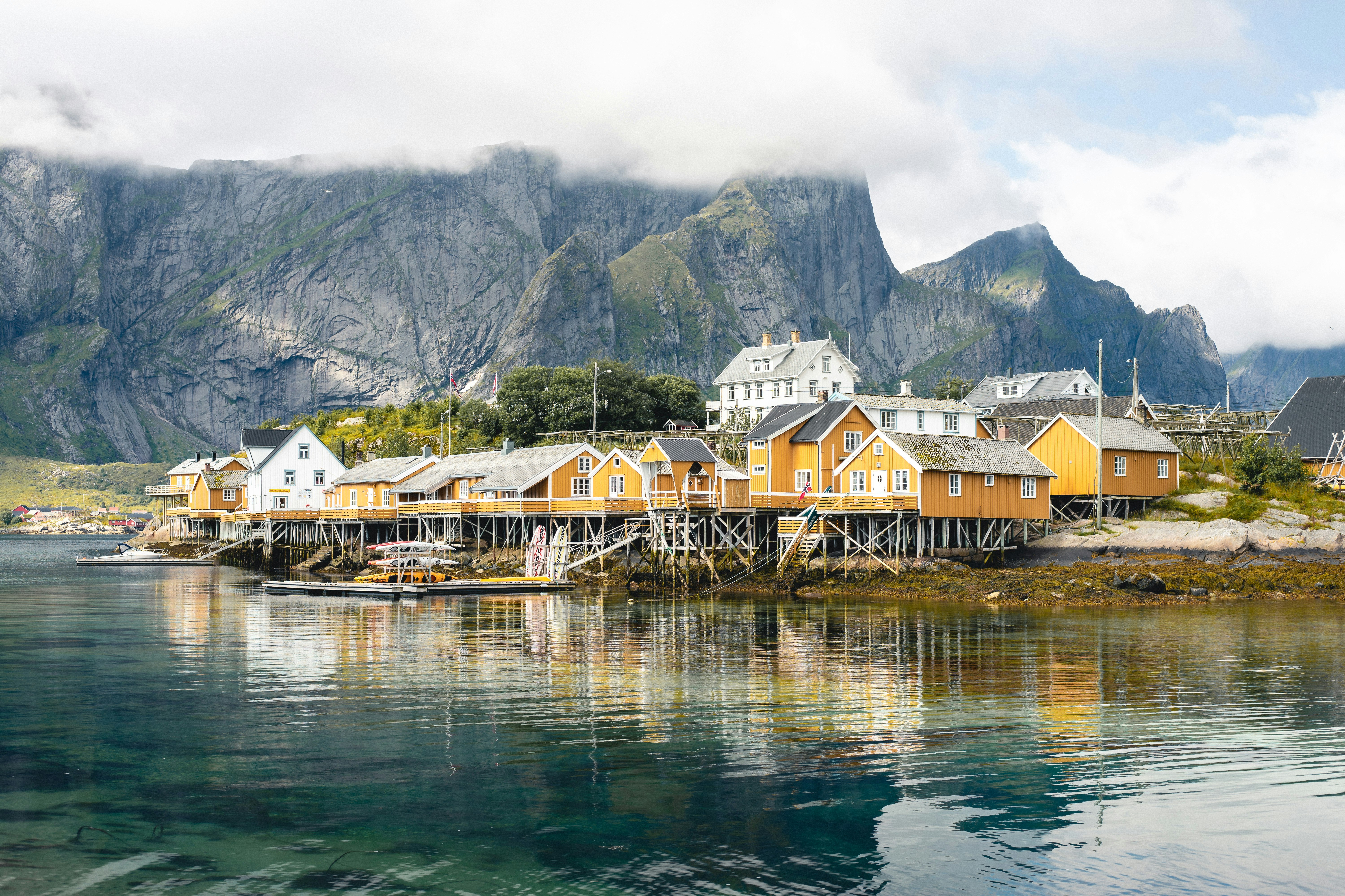 brown and white wooden houses near body of water and mountain during daytime